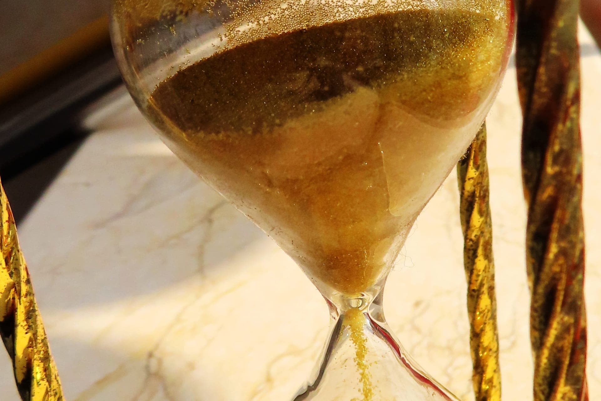 Close-up of an hourglass with golden sand flowing through